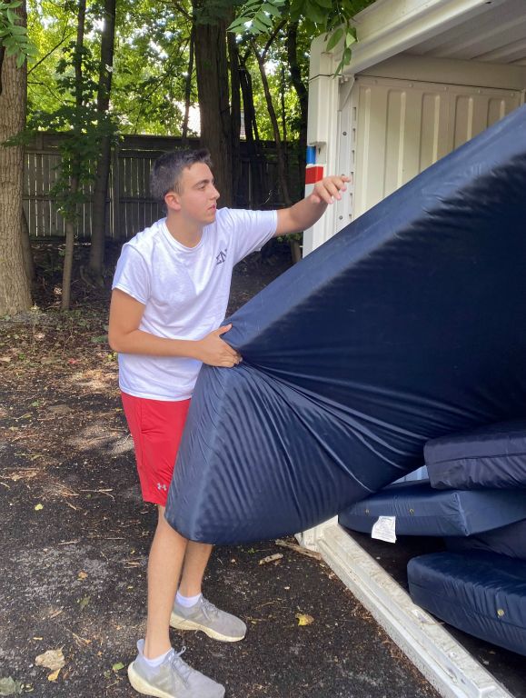 House manager Ben Wells ’25 removes a mattress from the storage pod out back.