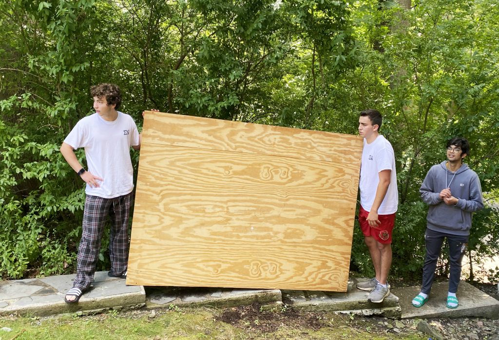 Tyler Angelica '25, Ben Wells '25 and Keshav Goel '25 move a bed frame into the house from storage.